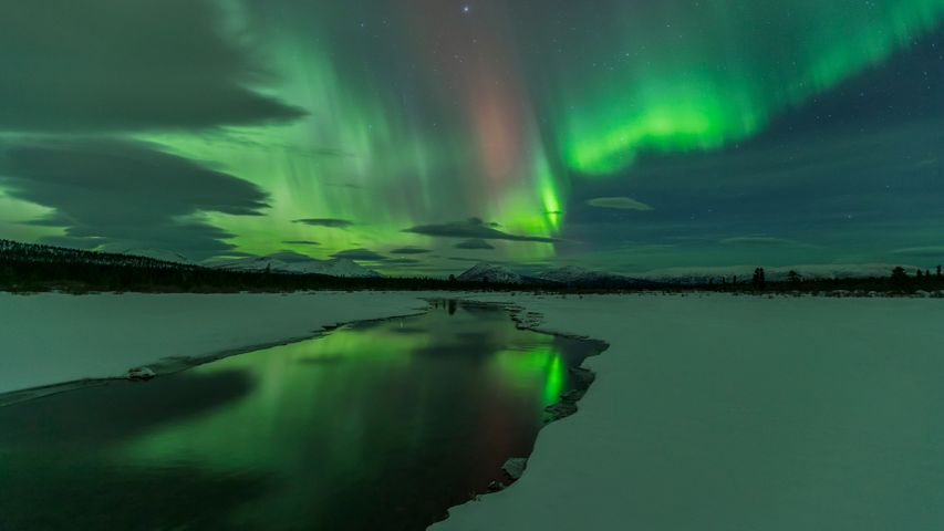 Northern Lights over open water in winter near Whitehorse, Yukon