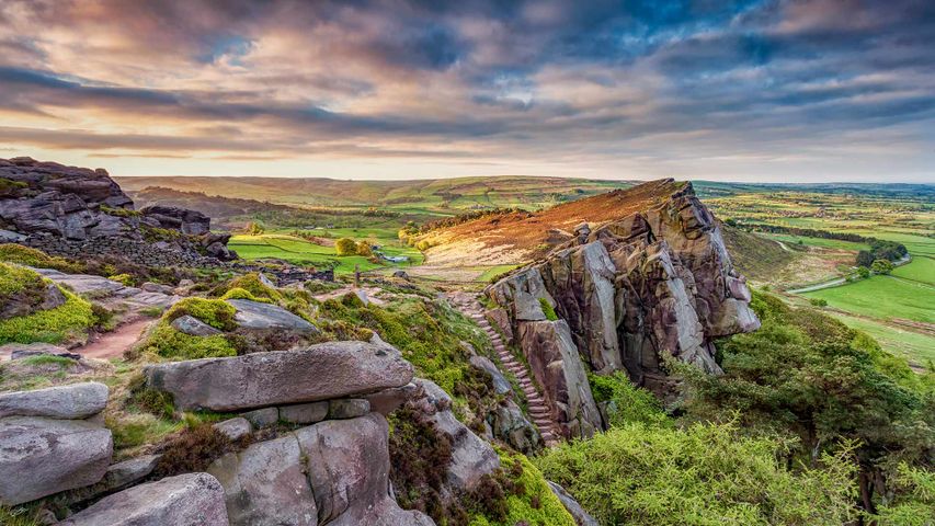 View of the rocky gritstone edge of The Roaches looking over the patchwork landscape, Peak District, Staffordshire.