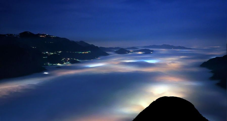 A layer of low clouds covers Olginate Lake and the villages around its banks, near Lake Como, Italy