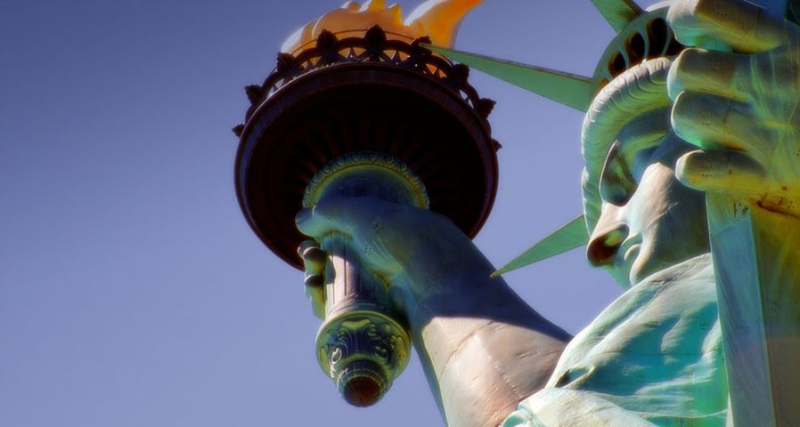 Detail of the Statue of Liberty showing the torch, flame, face, crown, robe and hand holding the tablet