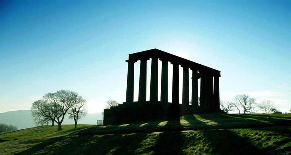 Early morning sun casts long shadows through silhouette of national monument in Calton hill, Edinburgh