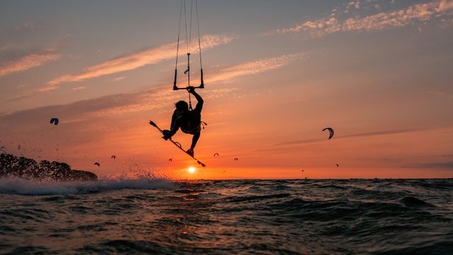 Silhouette eines springenden Kitesurfers bei Sonnenuntergang im baltischen Meer
