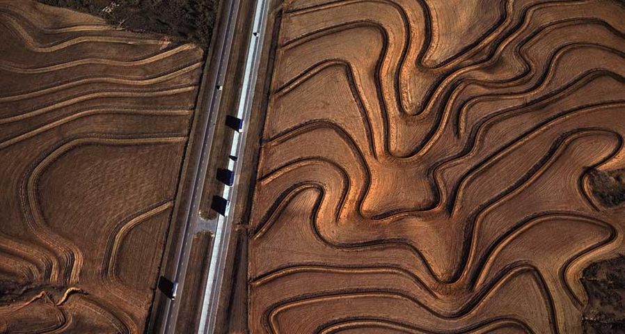 Highway 287 cuts through curving plowed fields near Carey, Texas