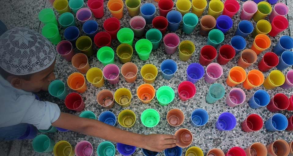 Ein Junge in Indien füllt Trinkbecher mit Wasser für das abendliche Fastenbrechen während des Ramadan – Jaipal Singh/Photolibrary ©