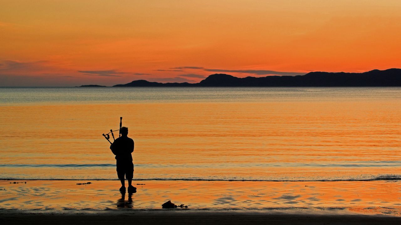 A bagpiper on Arisaig beach in Scotland