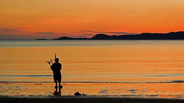 A bagpiper on Arisaig beach in Scotland