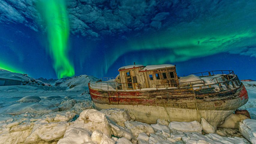 Northern lights over a stranded boat in Tasiilaq, Greenland
