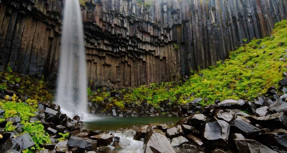 Svartifoss-Wasserfall, flankiert von schwarzen sechseckigen Basaltsäulen im  Skaftafell-Nationalpark, Island