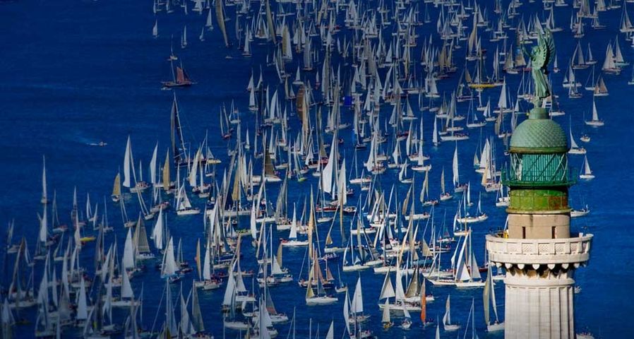 Teilnehmende Boote während der Segelregatta Barcolana in Triest, Italien. Im Vordergrund der Leuchtturm Faro della Vittoria – Grand Tour/Corbis ©