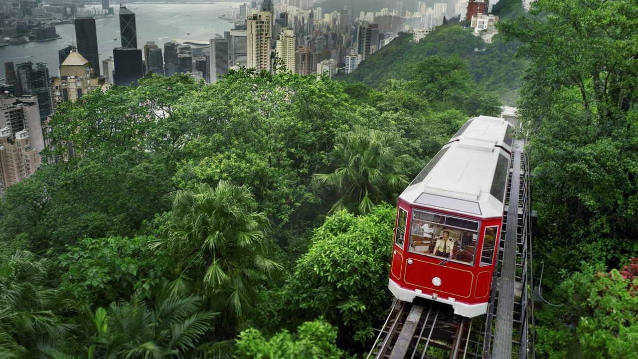 红色缆车驶过香港太平山顶，背景为香港城市风光