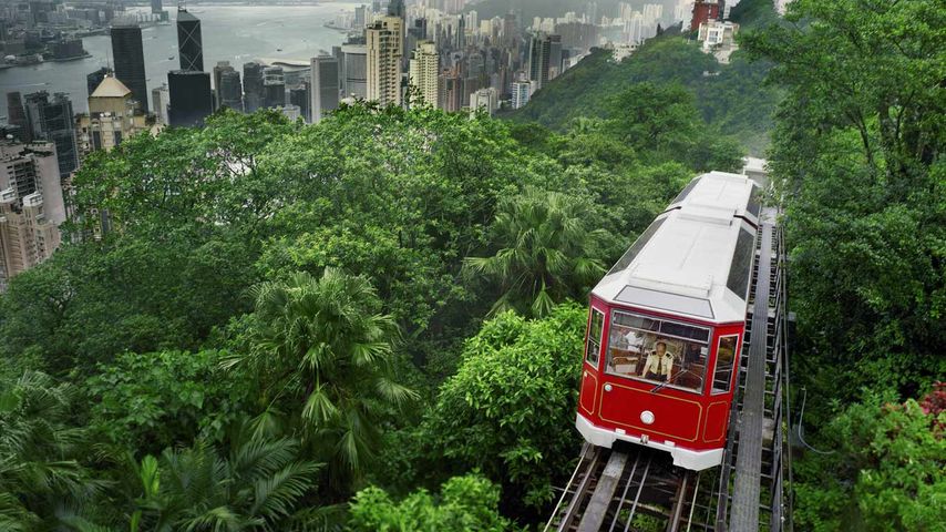 红色缆车驶过香港太平山顶，背景为香港城市风光