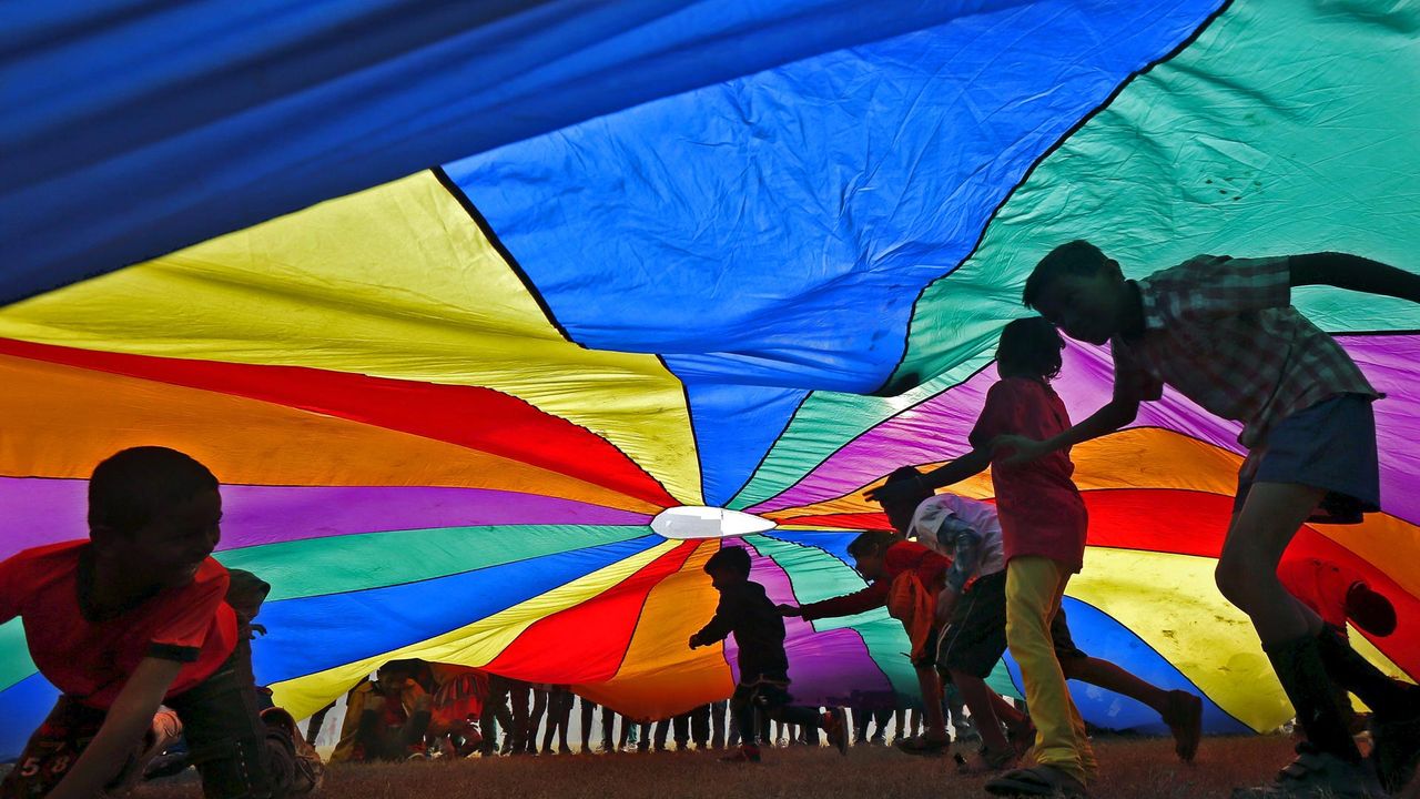 Children play under a parachute in Kolkata, India, for International Day of Friendship 