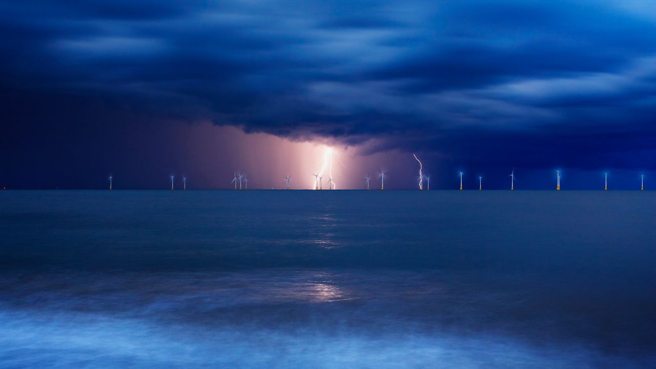 Offshore wind farm at Great Yarmouth in Norfolk in a lightning storm, England