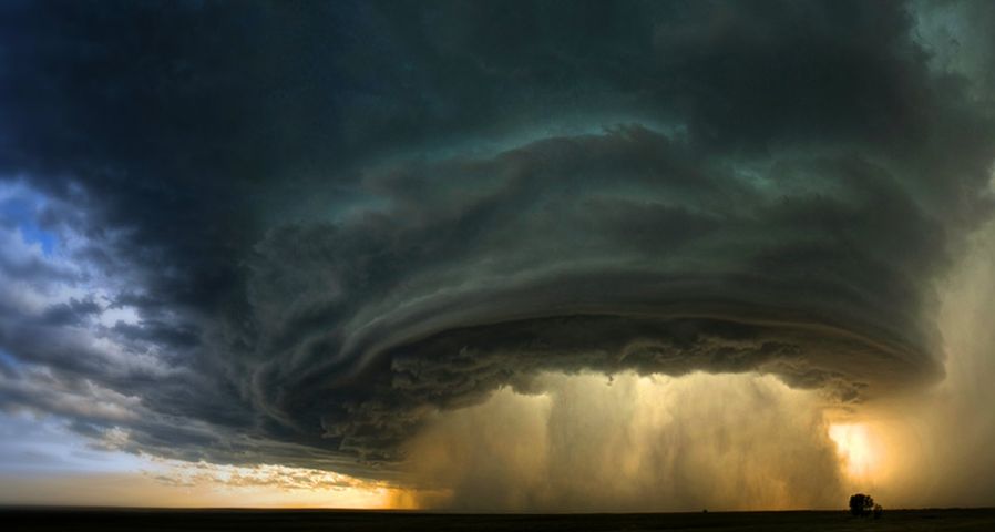 A supercell thunderstorm rolls across the Montana prairie at sunset