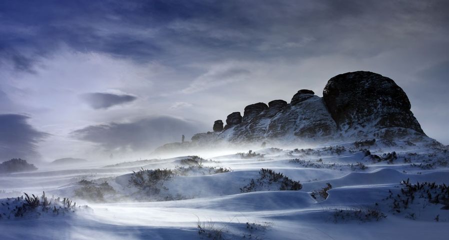 Haytor Rocks after a heavy snow fall, spin drift carried across the ground by strong winds, Dartmoor, Devon, England