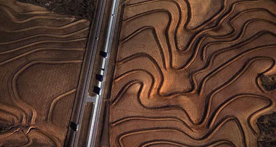 Highway 287 cuts through curving plowed fields near Carey, Texas, USA