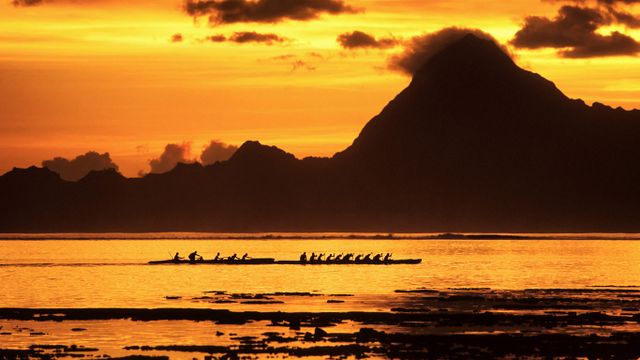 Course de pirogues polynésiennes dans le lagon au coucher du soleil, Tahiti 