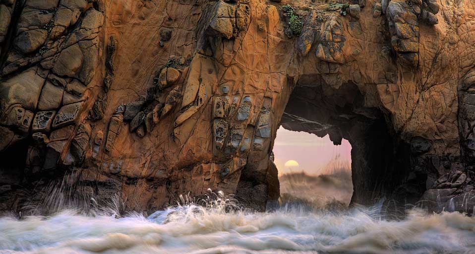 Waves and sea spray through a sea arch at Pfeiffer Beach in Big Sur, California