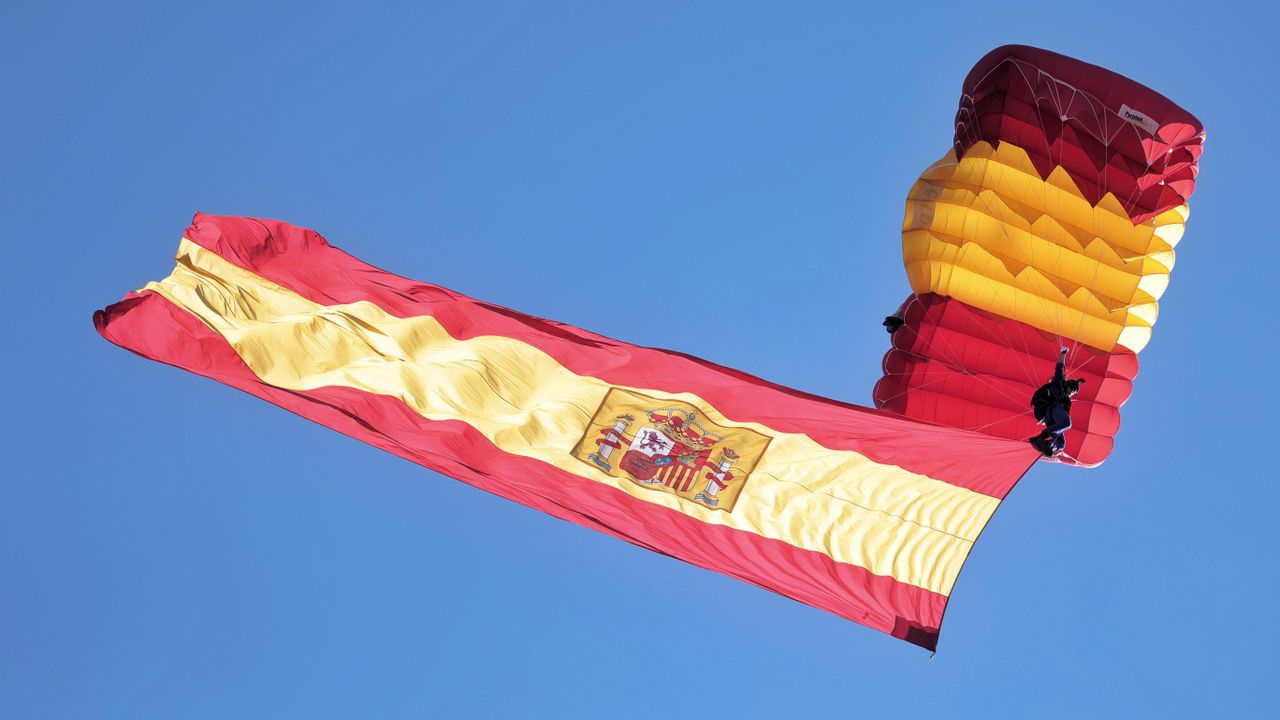 Paracaidista despliega la bandera española en el aire durante el desfile militar en el Día de la Hispanidad, Madrid, España