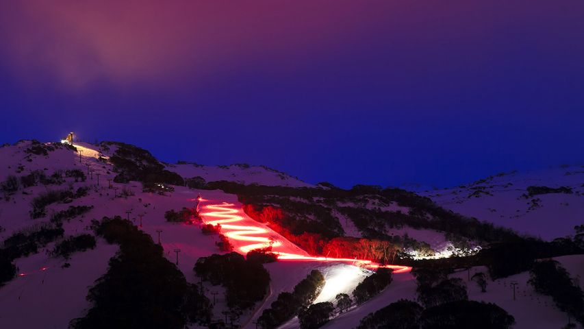 Skier with red torch at dusk in Thredbo, New South Wales 