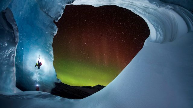 Climbing the Athabasca Glacier in Jasper National Park, Alberta, Canada, as the aurora borealis glows