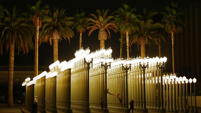 Des visiteurs dans la sculpture “Urban Light” de Chris Burden au LACMA de Los Angeles, Californie