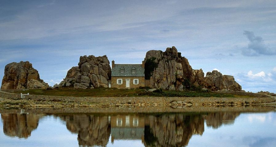House between rocks is reflected in Brittany, France