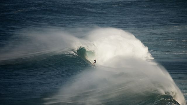 Surfer riding a wave in Nazaré, Portugal