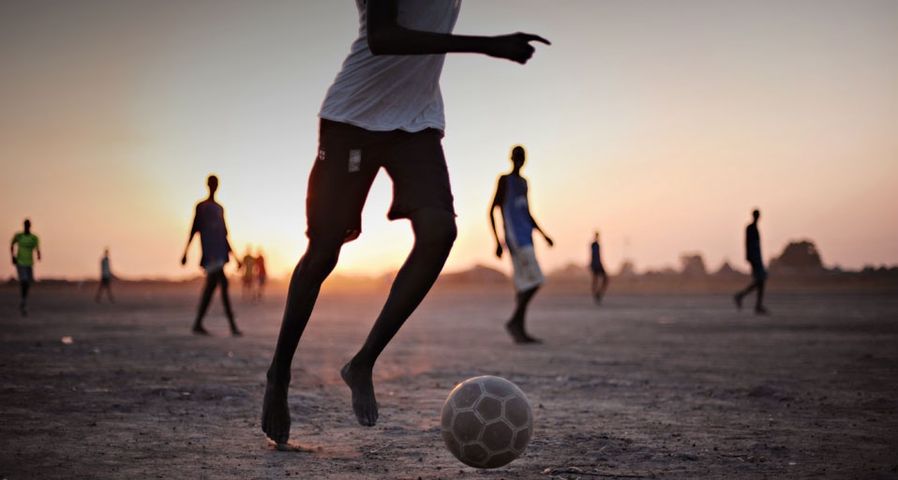 Boys play football on a dusty patch of land, Africa - Roberto Schmidt/Getty Images ©