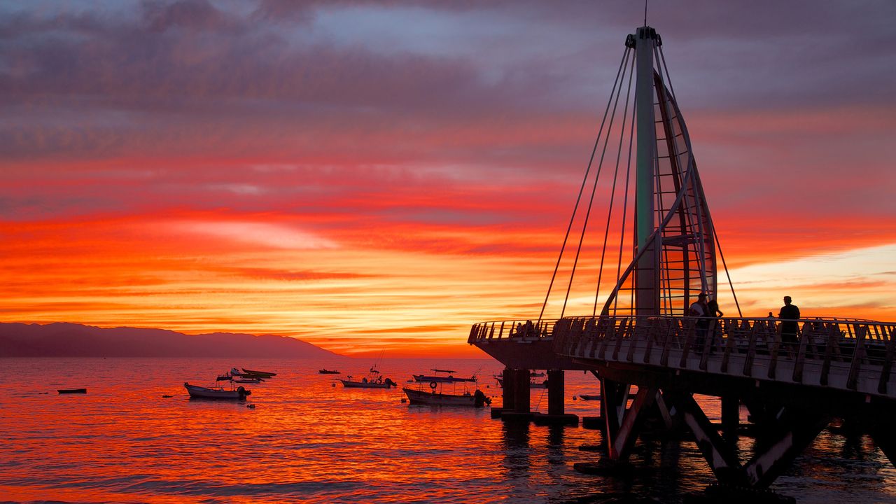 Los Muertos Pier and anchored boats under red evening sky, Puerto Vallarta, Mexico