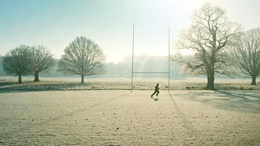 Man running in front of rugby post