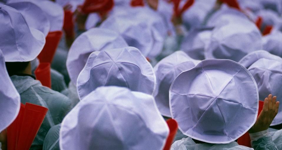 Students with white hats and red noisemakers at a baseball game in Osaka, Japan