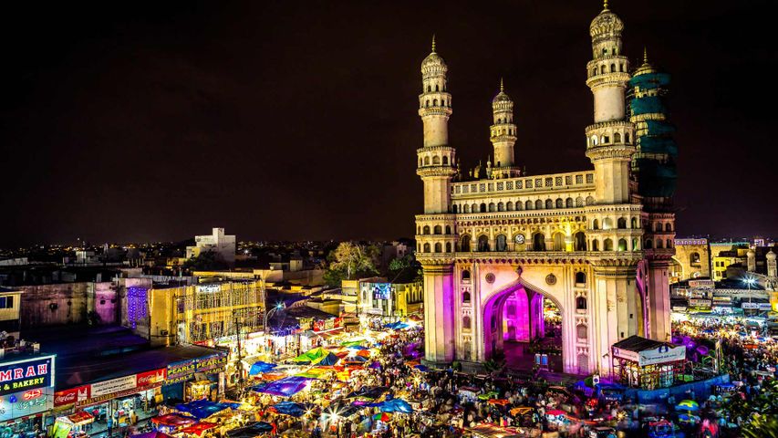 High angle view of illuminated Charminar amidst market at night.