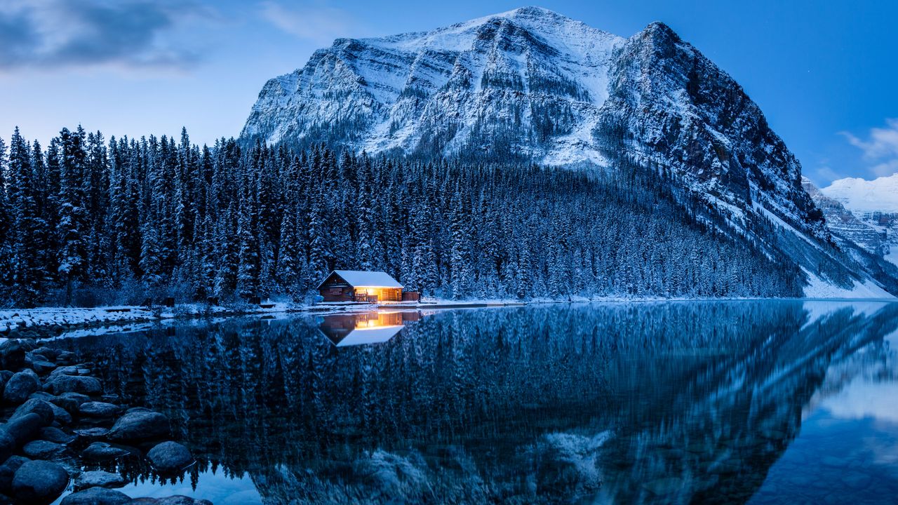 Illuminated log cabin, snow-covered mountains, winter forest, Lake Louise