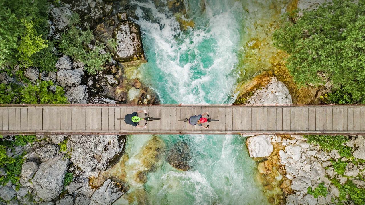 Cyclists on a wooden bridge over the river Soča, Triglav National Park, Slovenia