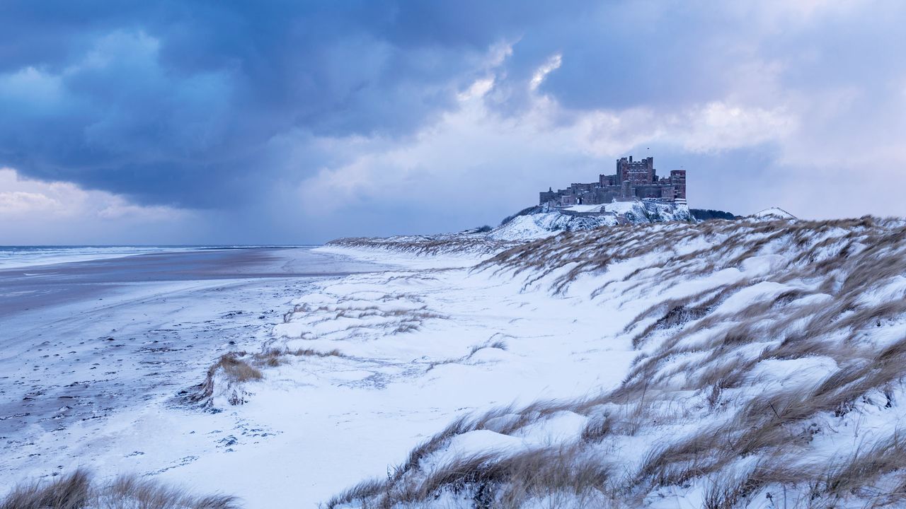 Bamburgh Castle and sand dunes after snowfall in Northumberland