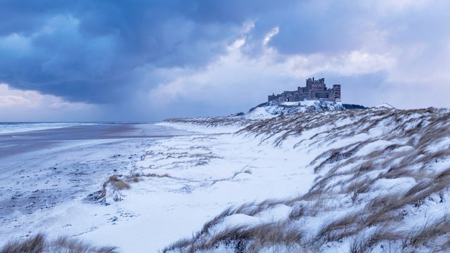 Bamburgh Castle and sand dunes after snowfall in Northumberland