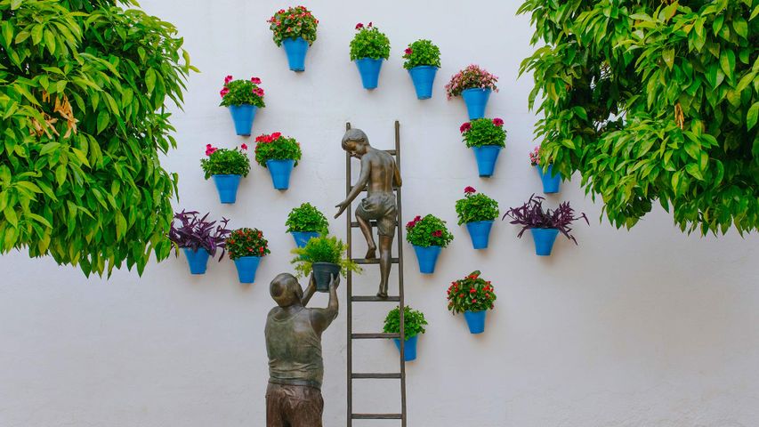 Bronzeskulptur eines Kindes und seines Großvaters bei der Pflege von Pflanzen und Blumen, Córdoba, Spanien