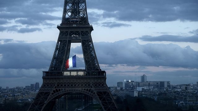 Le drapeau français flottant au centre de la Tour Eiffel, le 11 mars 2020, lors d’une cérémonie pour la première Journée nationale d’hommage aux victimes du terrorisme