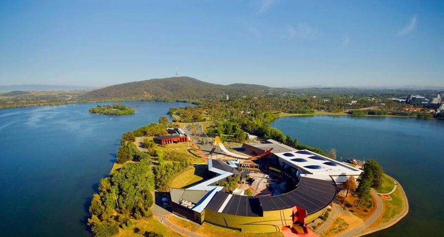 Aerial shot of the National Museum of Australia, surrounded by Lake Burley Griffin with Black Mountain in the background, Canberra, ACT