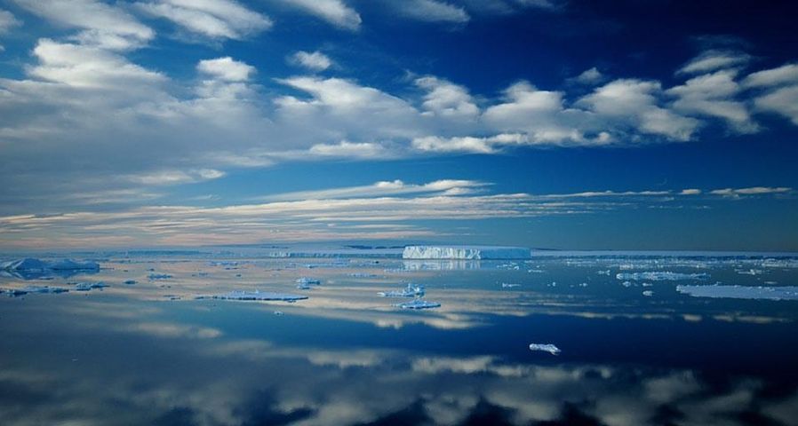 Iceberg and cloud landscape reflecting in totally calm waters near Ross Island, Antarctica, Southern Ocean