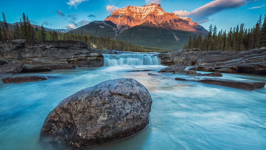 Sunset lights up Mount Fryatt as the Athabasca River flows over Athabasca Falls in Jasper National Park, Alberta, Canada