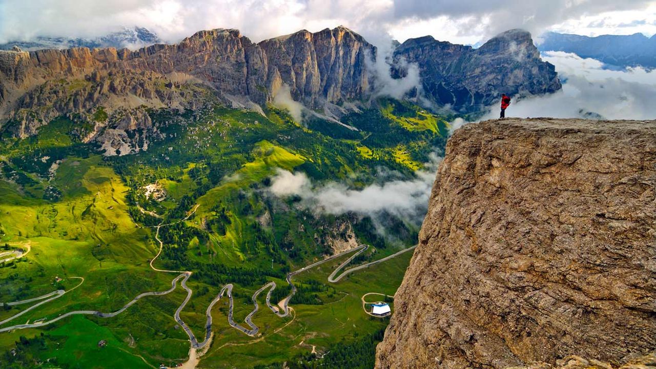 Randonneur sur le massif du Groupe de Sella, admirant la route allant du val Badia au val Gardena, Dolomites, Sud-Tyrol, Italie