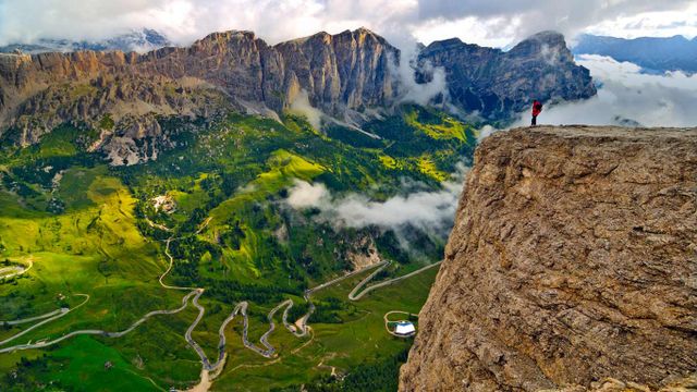 Randonneur sur le massif du Groupe de Sella, admirant la route allant du val Badia au val Gardena, Dolomites, Sud-Tyrol, Italie