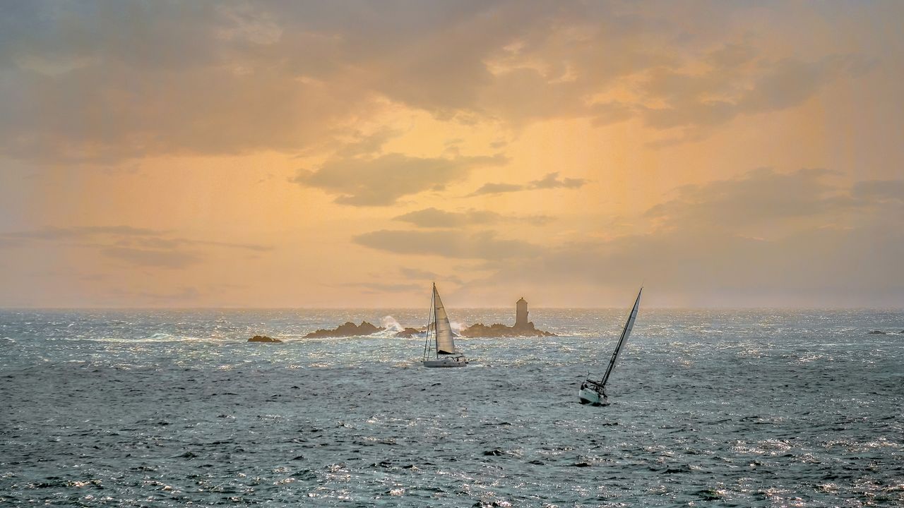 Voiliers au crépuscule devant un phare au large de Roscoff, Finistère, Bretagne