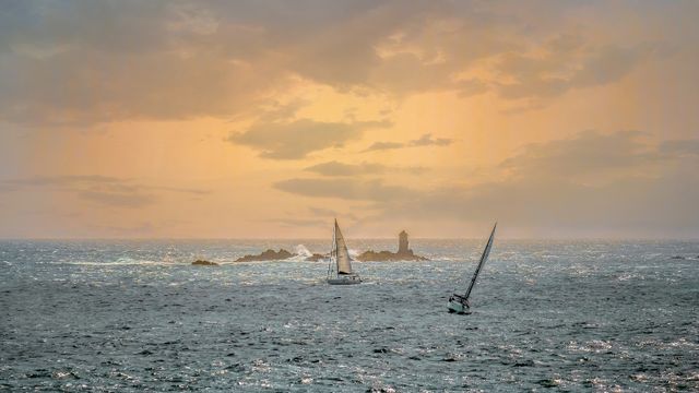 Voiliers au crépuscule devant un phare au large de Roscoff, Finistère, Bretagne