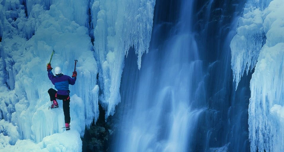 Ice climber ascending a frozen waterfall in Telluride, Colorado, USA
