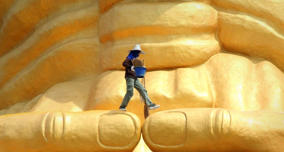 A worker walks across the Luang Pu Thuad statue near Ayutthaya, Thailand