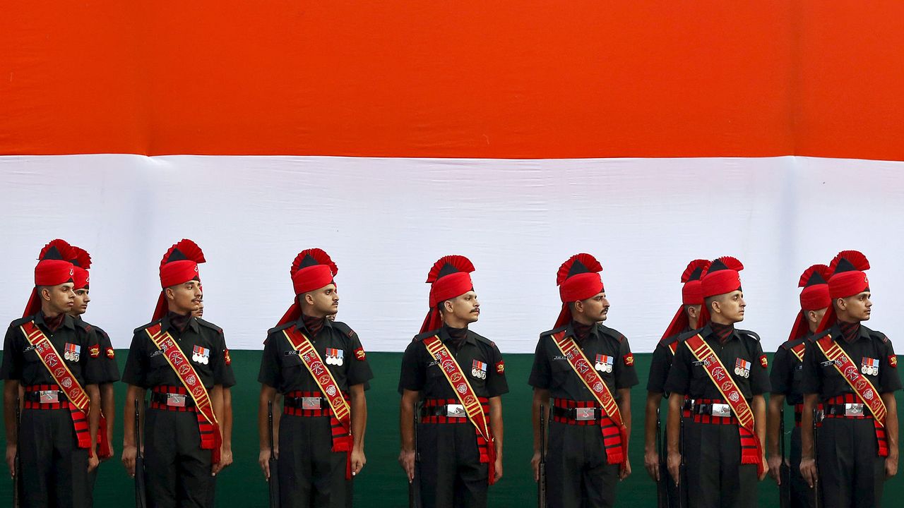 Soldiers stand guard in front of a tricolour flag rehearsal