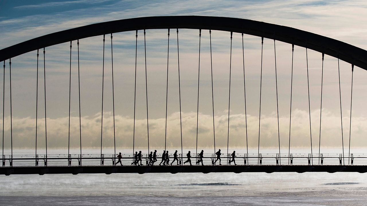 Joggers run across the Humber Bay Arch Bridge in Toronto, Canada 